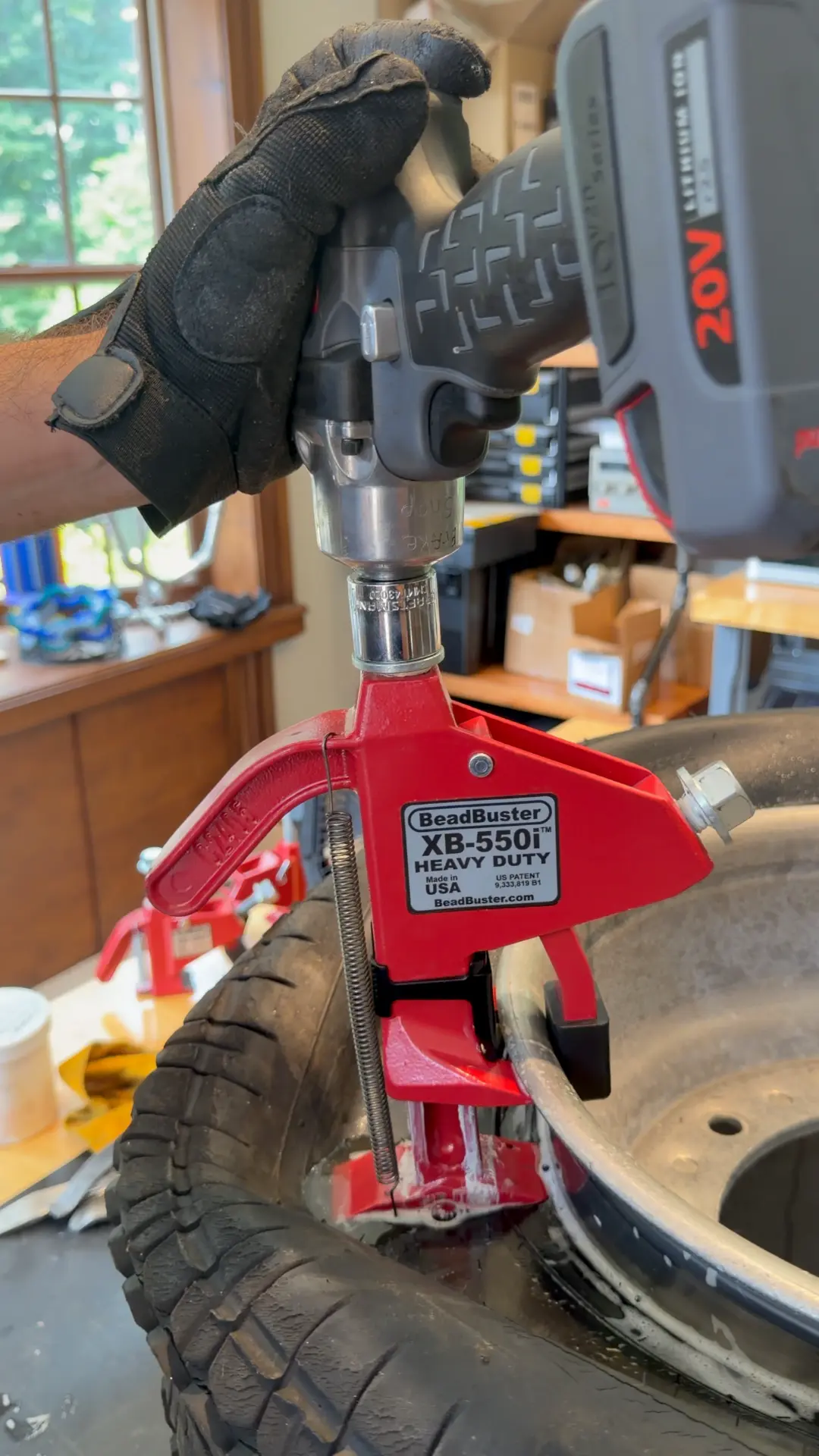 BeadBuster XB-550i clamped to a wheel rim and driven by a cordless impact wrench to push the bead down